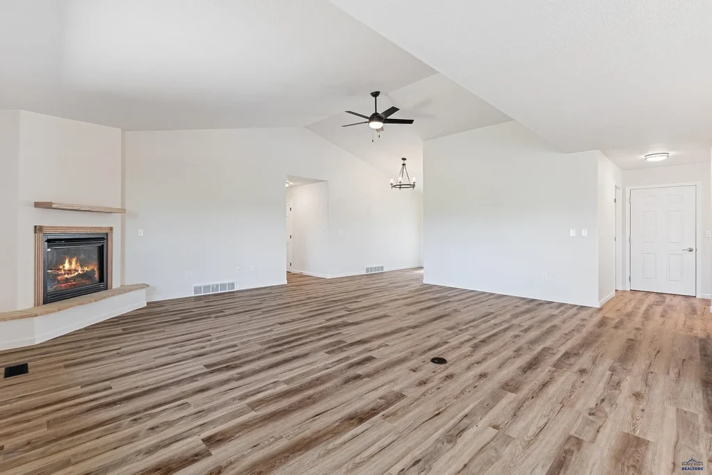 New wood-look vinyl plank flooring installed by CNT Builders, a flooring contractor in Spearfish, SD, in a modern open-concept living space with a corner fireplace
