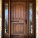 Custom solid wood entry door by CNT Builders in Spearfish, SD, designed with vertical panels, wrought iron accents, and sidelights.